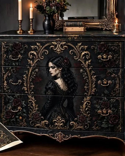 A dark, ornate Gothic-style wooden dresser or chest with three drawers, decorated with intricate gold filigree, red roses, and a painted portrait of a woman in a black dress on the front. The dresser is styled in a moody room setting with candles, books, and a mirror on top.