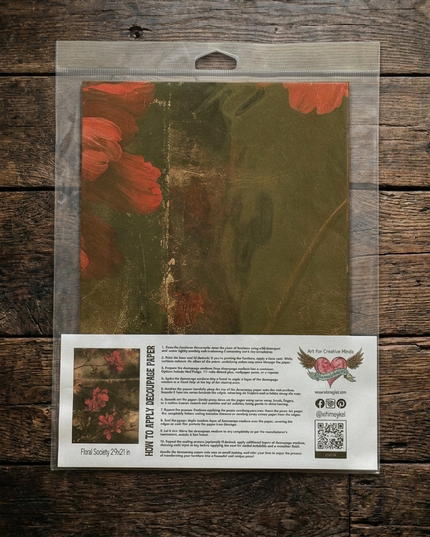 Packaged decorative paper featuring a vintage-style floral design in muted red and olive green tones, sealed in a clear plastic bag with a printed instruction and branding card below, displayed on a rustic dark wood background.