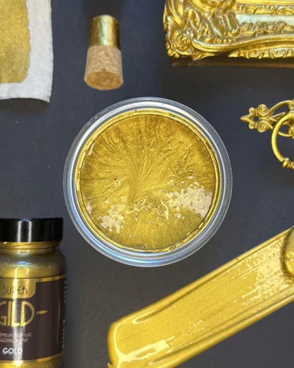 Gold paint can, brush, and decorative elements on a dark surface